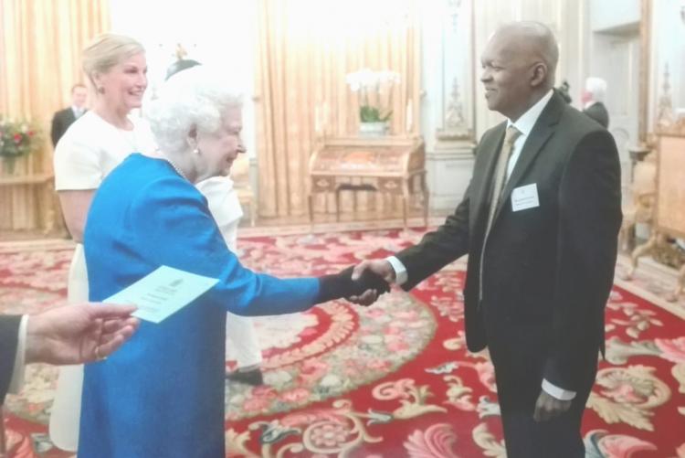 Dr. Stephen Gichuhi (right) meets Her Majesty Queen Elizabeth at Buckingham Palace.